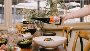 A dining table set with plates, glasses, and a bottle being poured. - Flowerdale Estate (Strath Creek)