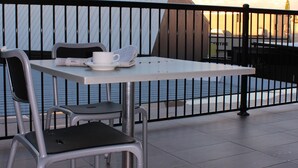 A balcony with a table and chairs, a white cup, and a newspaper. - The Premier Hotel (Broadmeadow)