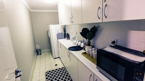 A compact kitchen with white cabinets, a microwave, and a sink. - The Premier Hotel (Broadmeadow)
