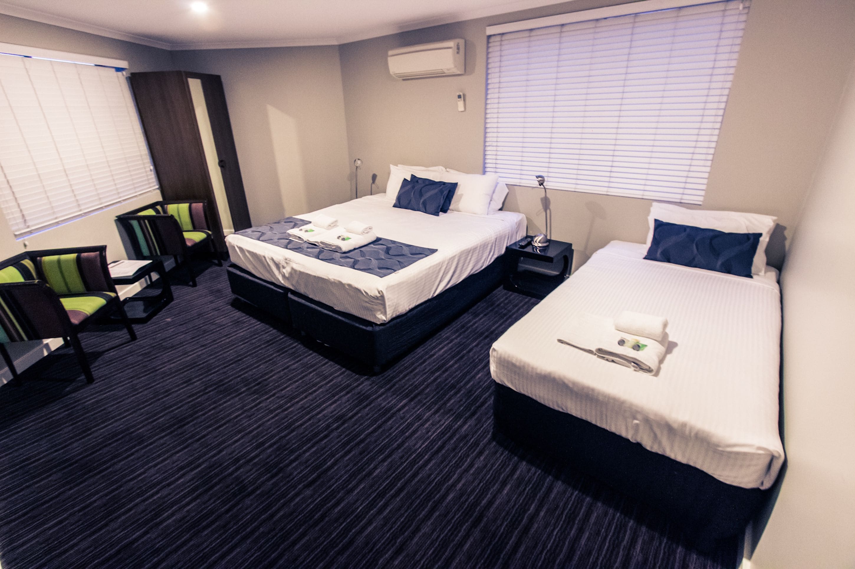 A hotel room with two beds, a desk, and a chair.