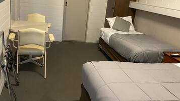 A hotel room with a bed, a desk with a chair, a door, and a wall-mounted TV.
