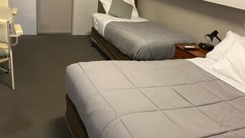Una habitación de hotel con dos camas, un armario de madera, un escritorio y una silla.