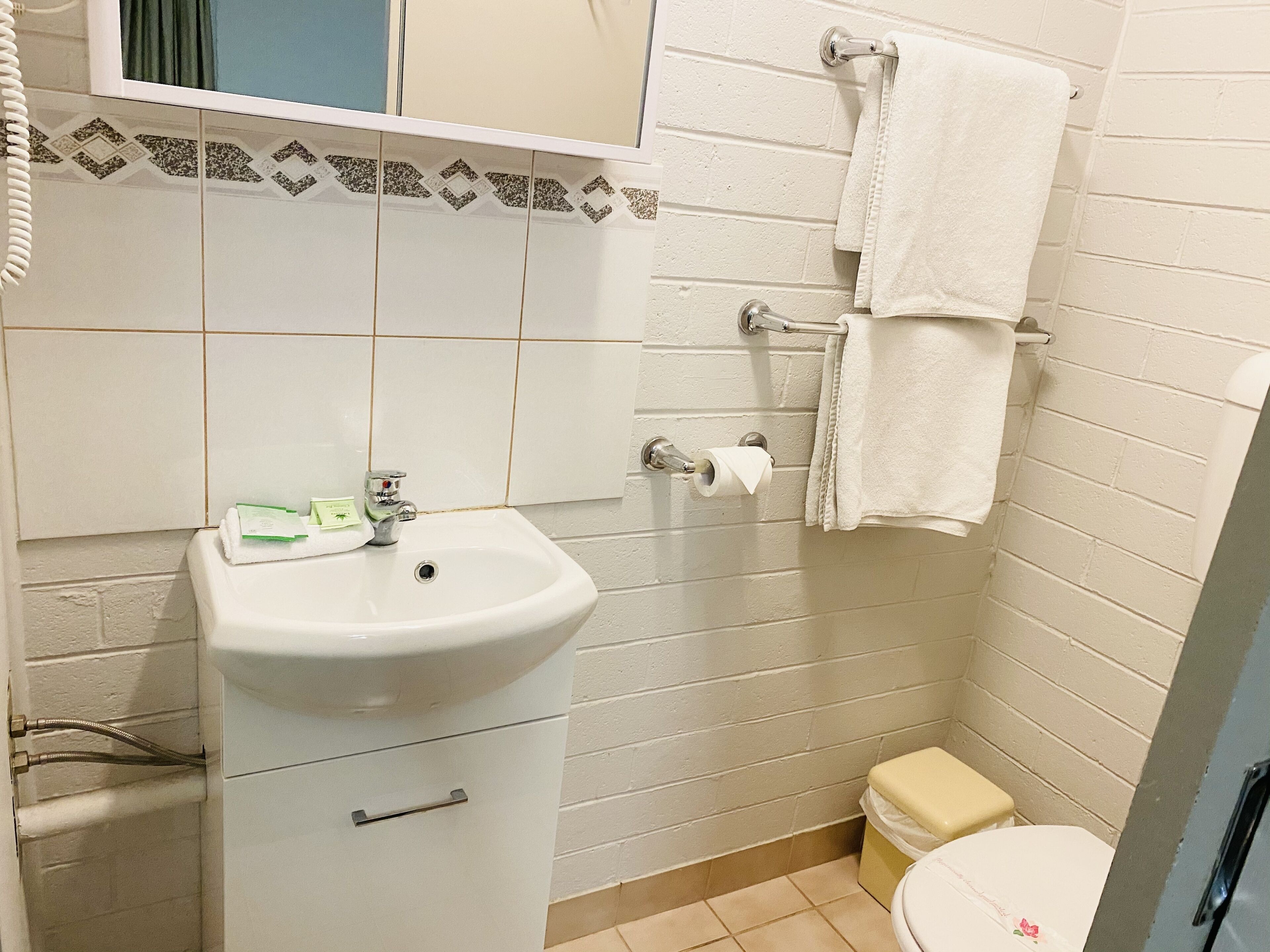A small bathroom with a white sink, a toilet, and a towel rack.