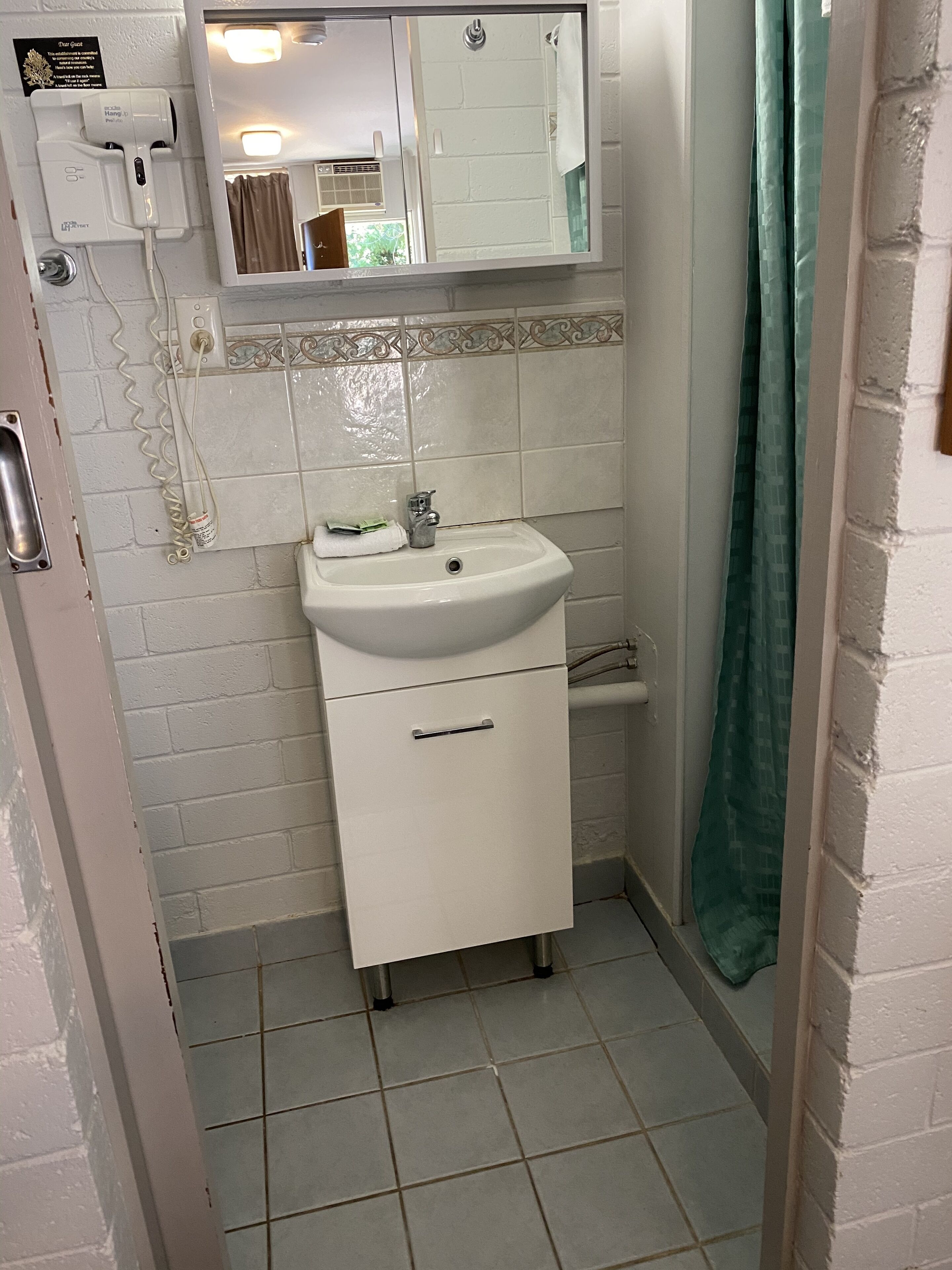 A bathroom with a white sink, a mirror above it, and a shower curtain.
