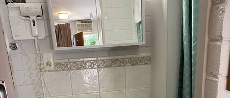 A bathroom with a white sink, a mirror above it, and a shower curtain.