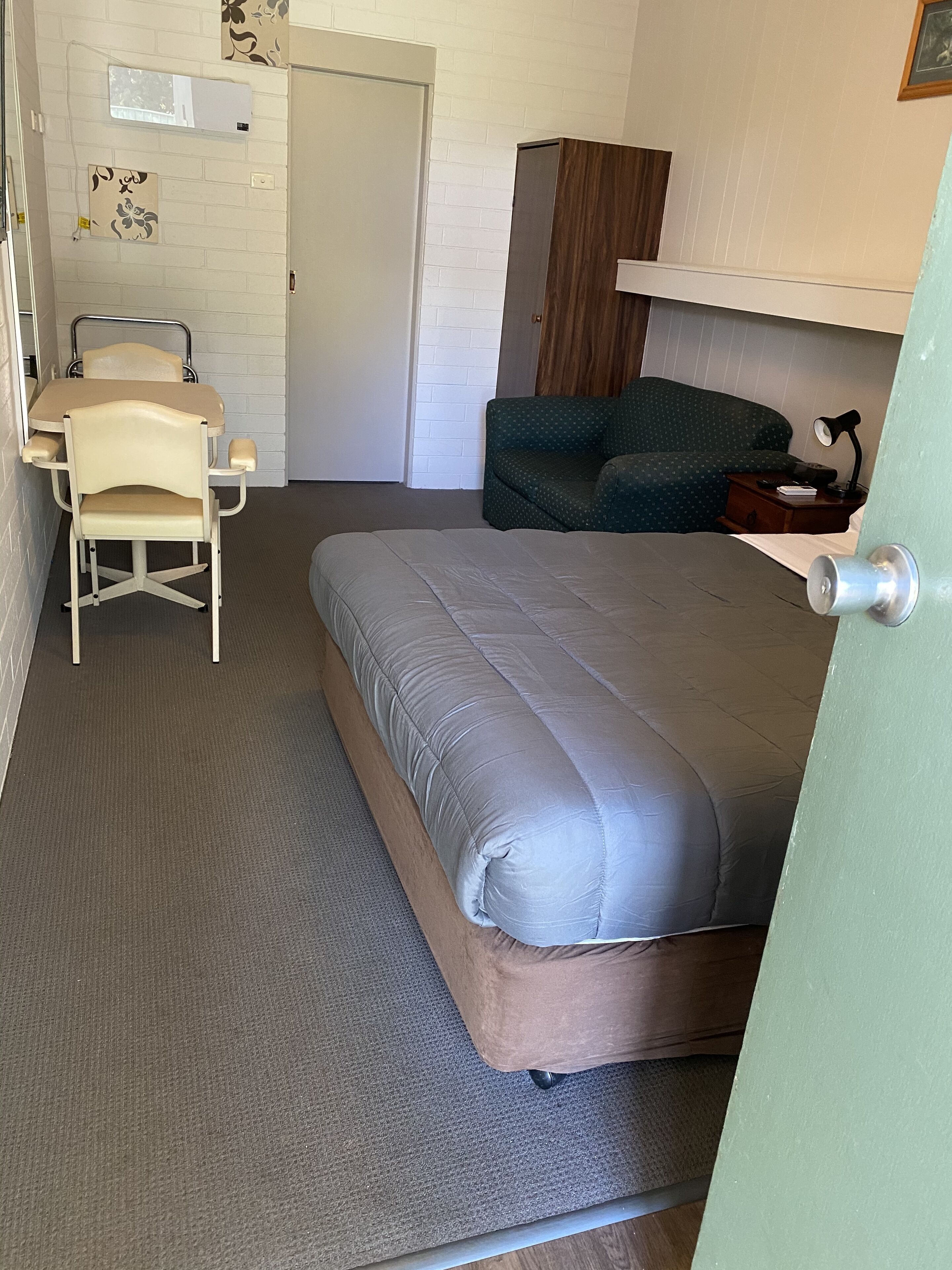 Ein Zimmer mit einem Bett, einem Sessel, einem kleinen Tisch und einer Couch.
