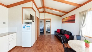 Une cuisine moderne avec des poutres en bois, un coin repas avec une table et des chaises, et un espace de vie avec un canapé et un téléviseur.