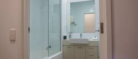 Un baño moderno con cabina de ducha de vidrio, un lavabo y un espejo.