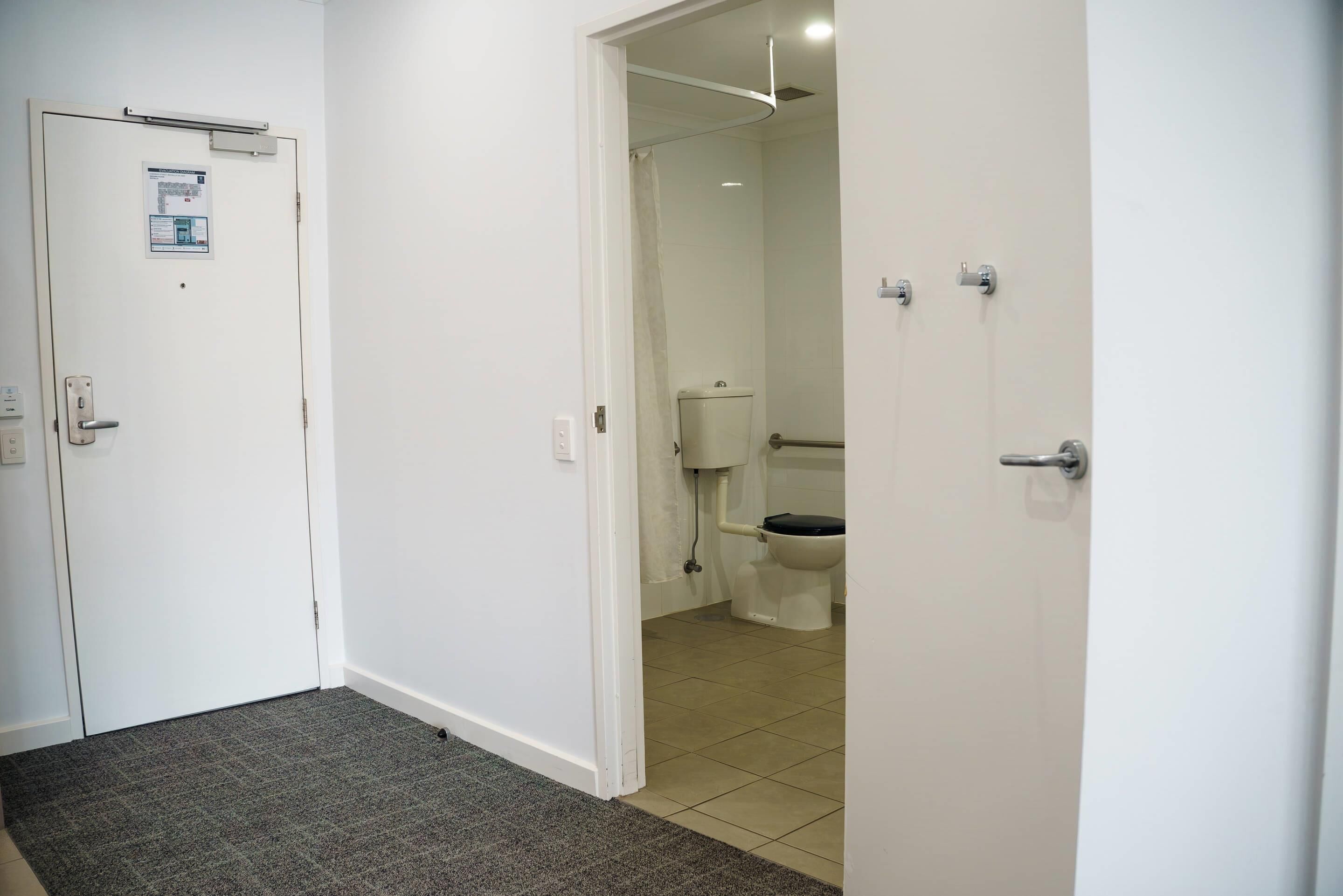 A hallway leading to a bathroom with a toilet and a shower area.