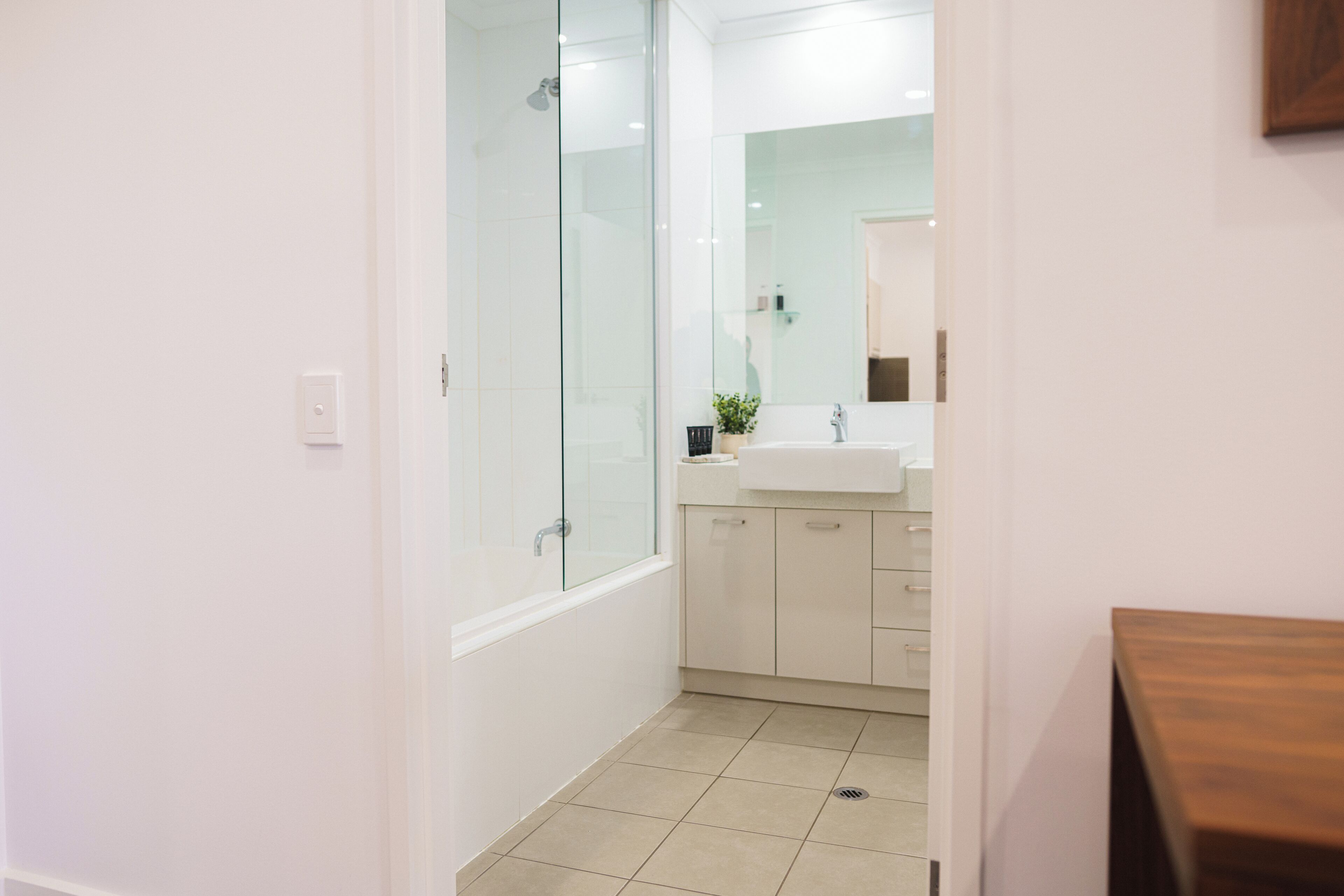 Un baño moderno con cabina de ducha de vidrio, un lavabo blanco y un espejo encima.