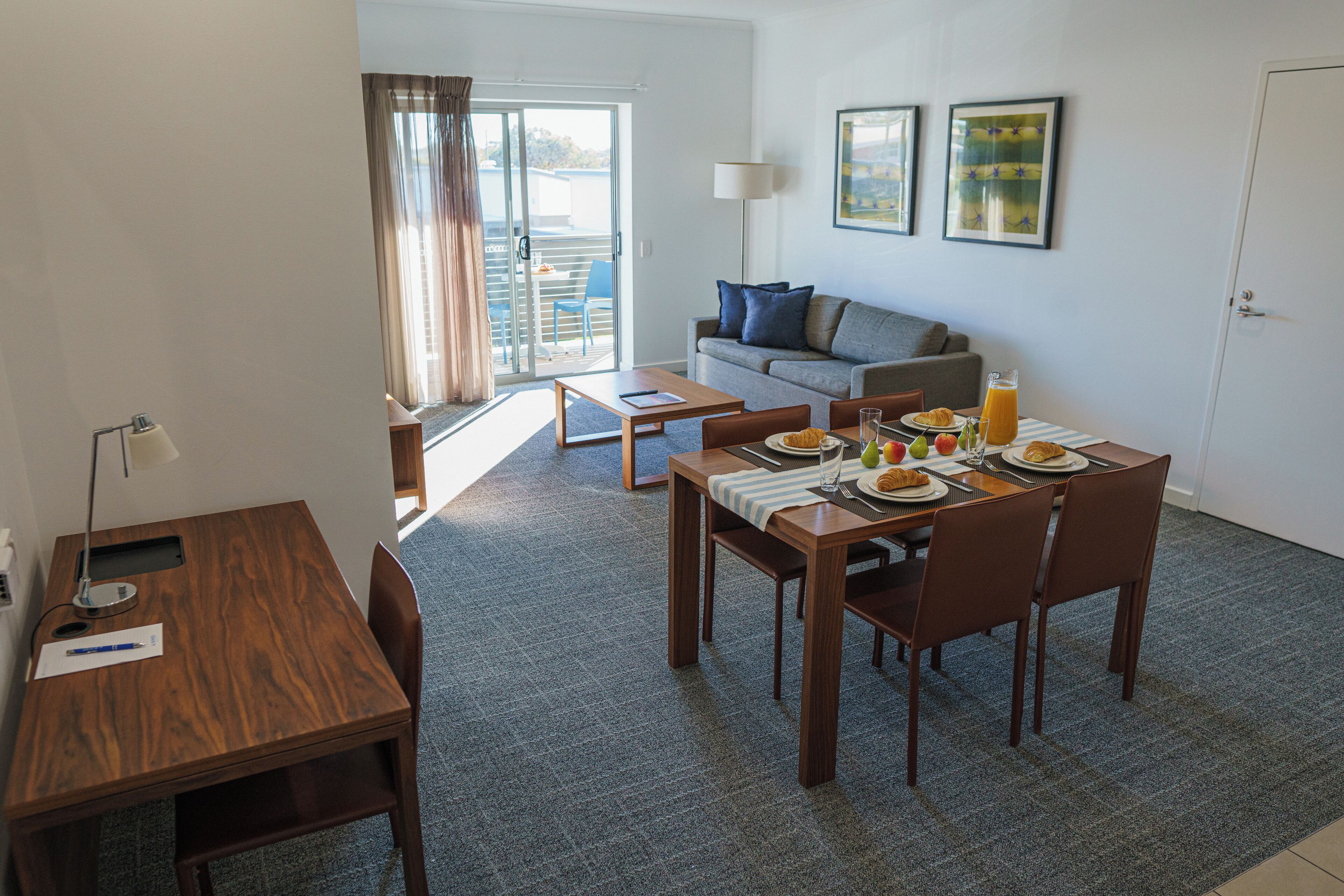 Ein modernes, helles Wohnzimmer mit Essbereich, einer Couch und einem Balkon mit Blick.
