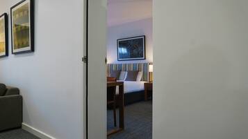 A hotel room with a bed, bedside table, lamp, and a framed picture on the wall.