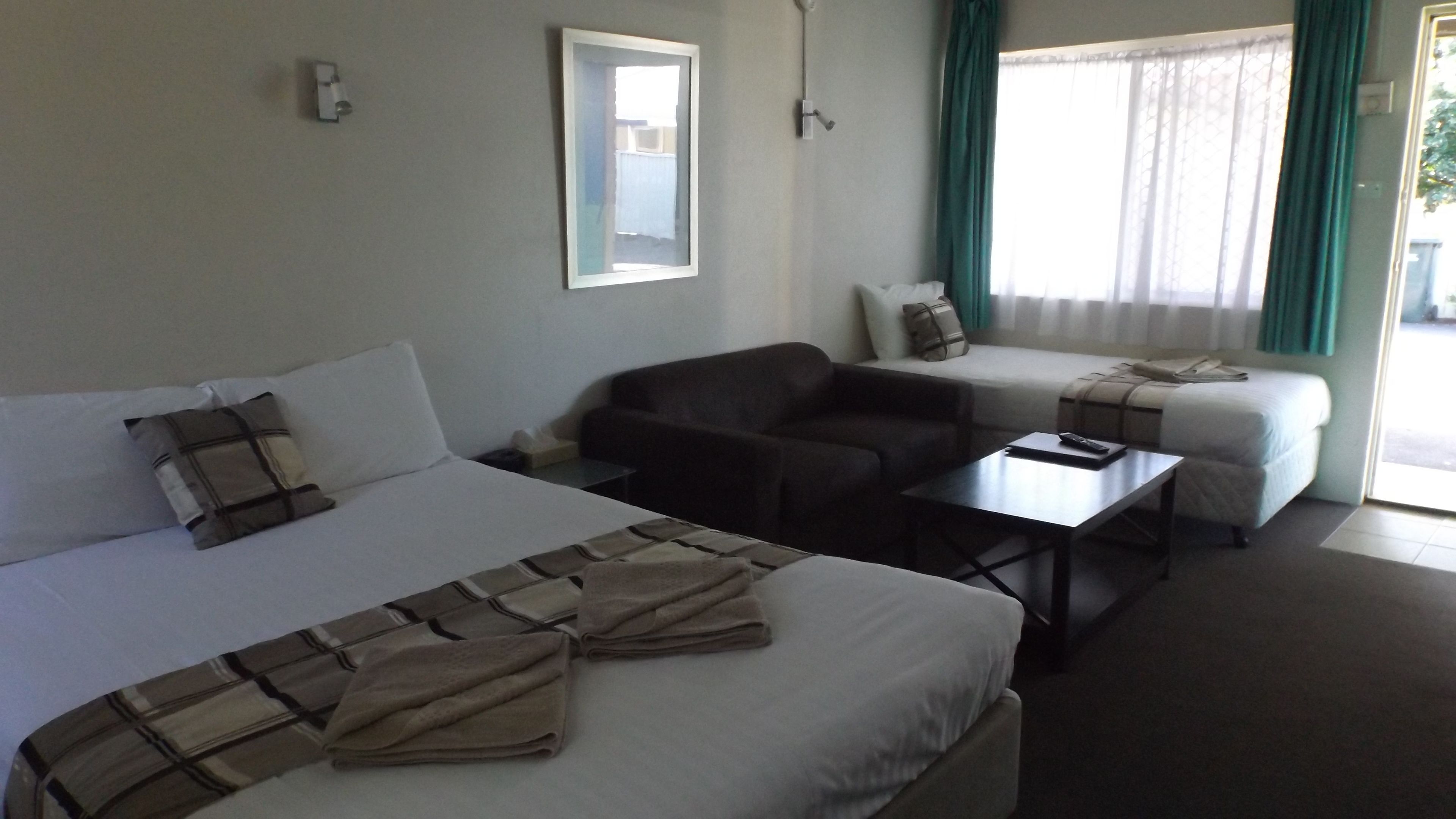 Een hotelkamer met een bed, een bank, een bureau en een raam met gordijnen.