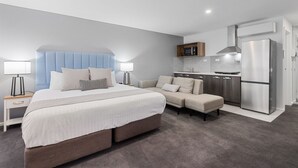 Une chambre d’hôtel moderne dotée d’un grand lit, d’un canapé, d’une kitchenette et d’une salle de bain séparée.