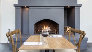 Une table à manger avec deux chaises, une cheminée et une bouteille de vin.