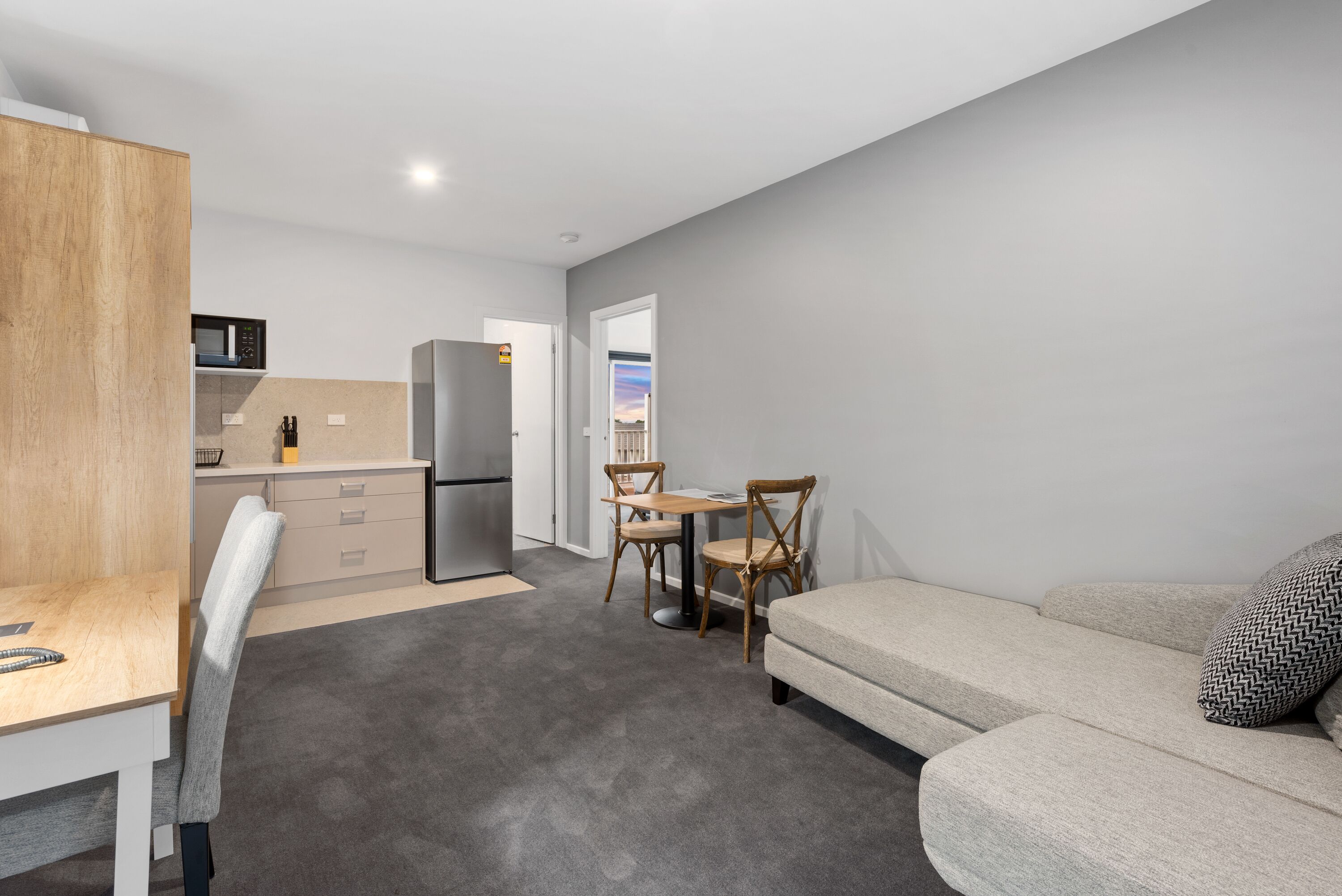 A modern, compact living space with a kitchenette, a dining area, and a sofa.