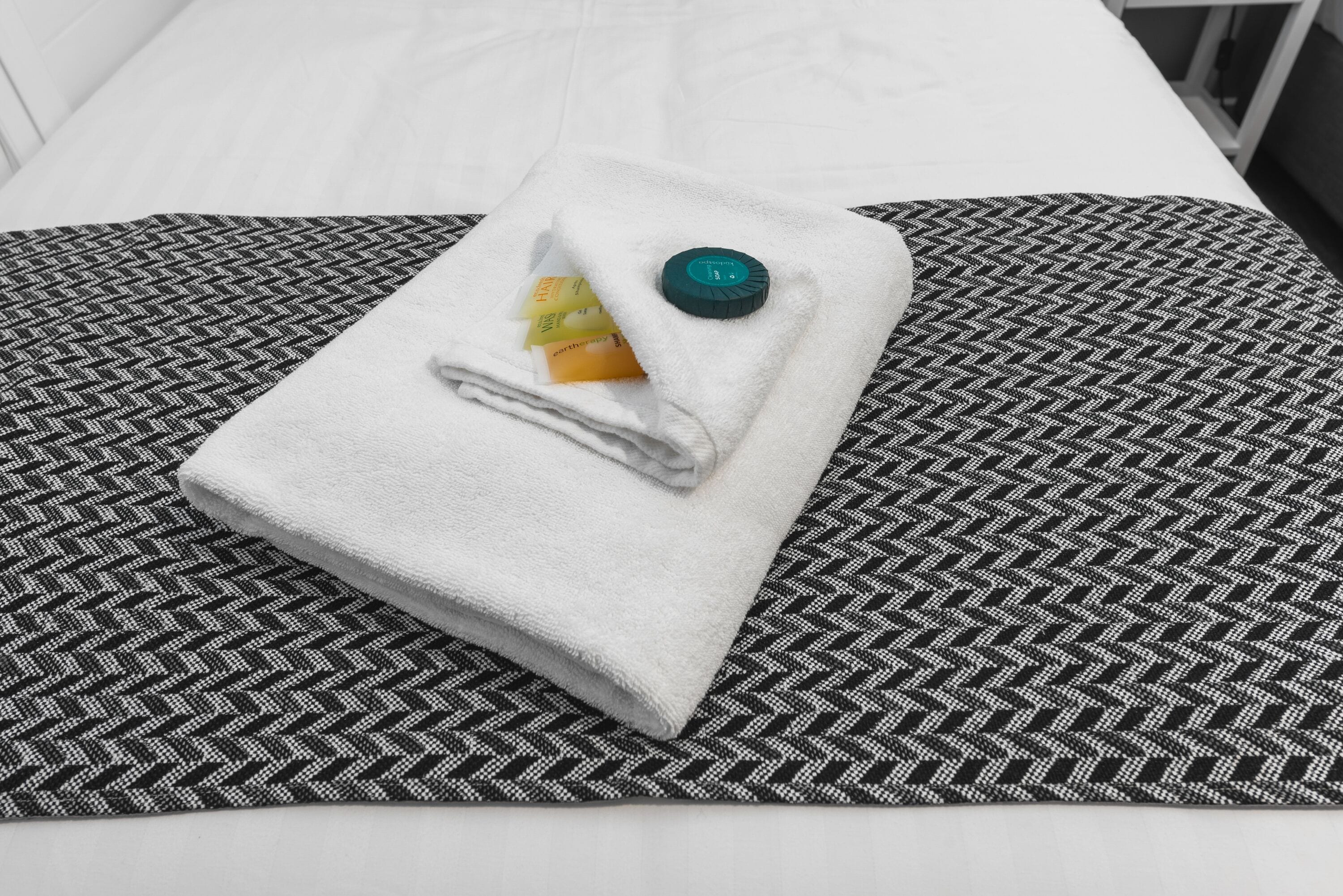 A neatly folded white towel on a black and white patterned bedspread.