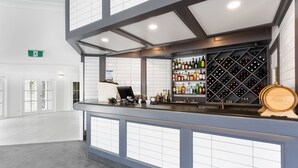 Un espace bar moderne comprenant un présentoir à bouteilles de vin, une caisse enregistreuse et un tonneau en bois.