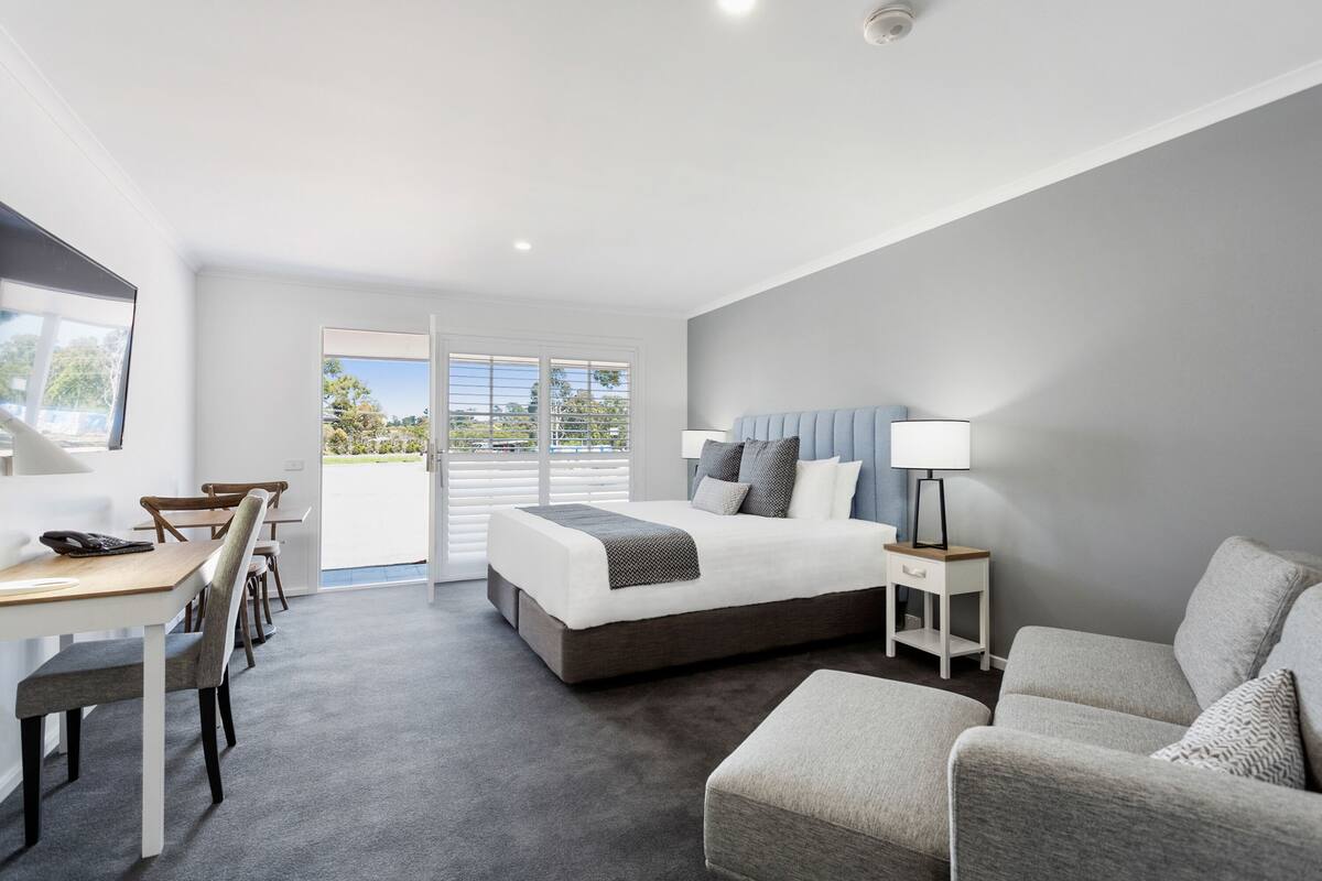 A modern bedroom with a large bed, a desk, and a sofa.