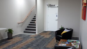 A lobby with a staircase, a reception desk, and a seating area. - Northpark Motel (Timaru)