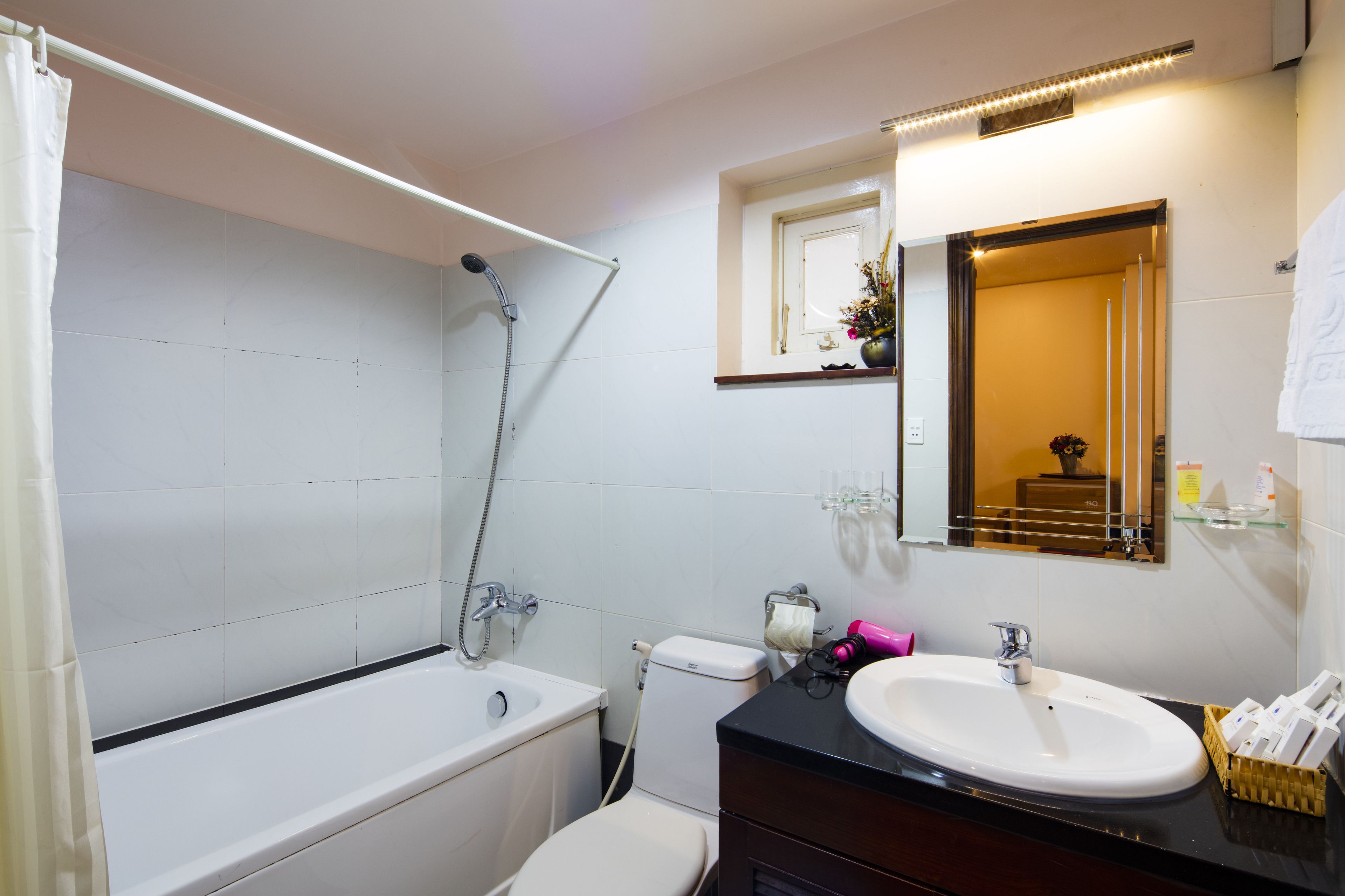 A bathroom with a bathtub, toilet, sink, and a mirror.