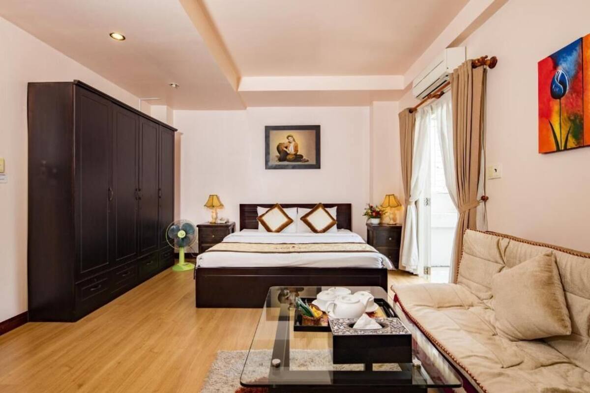 A bedroom with a bed, a sofa, a cabinet, and a painting on the wall.