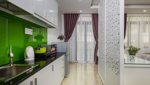 A modern kitchen with white cabinets, a green backsplash, and a stainless steel sink.