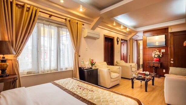 A hotel room with a large bed, a sofa, a desk, and a TV.