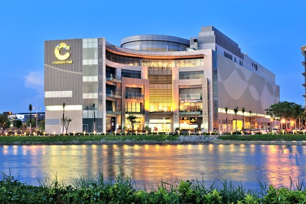 A modern building with a crescent mall sign, multiple floors, and a reflection in the water.
