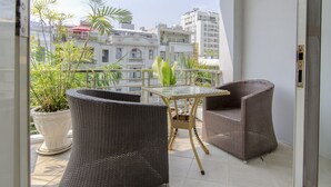 A balcony with wicker furniture, a glass table, and potted plants.