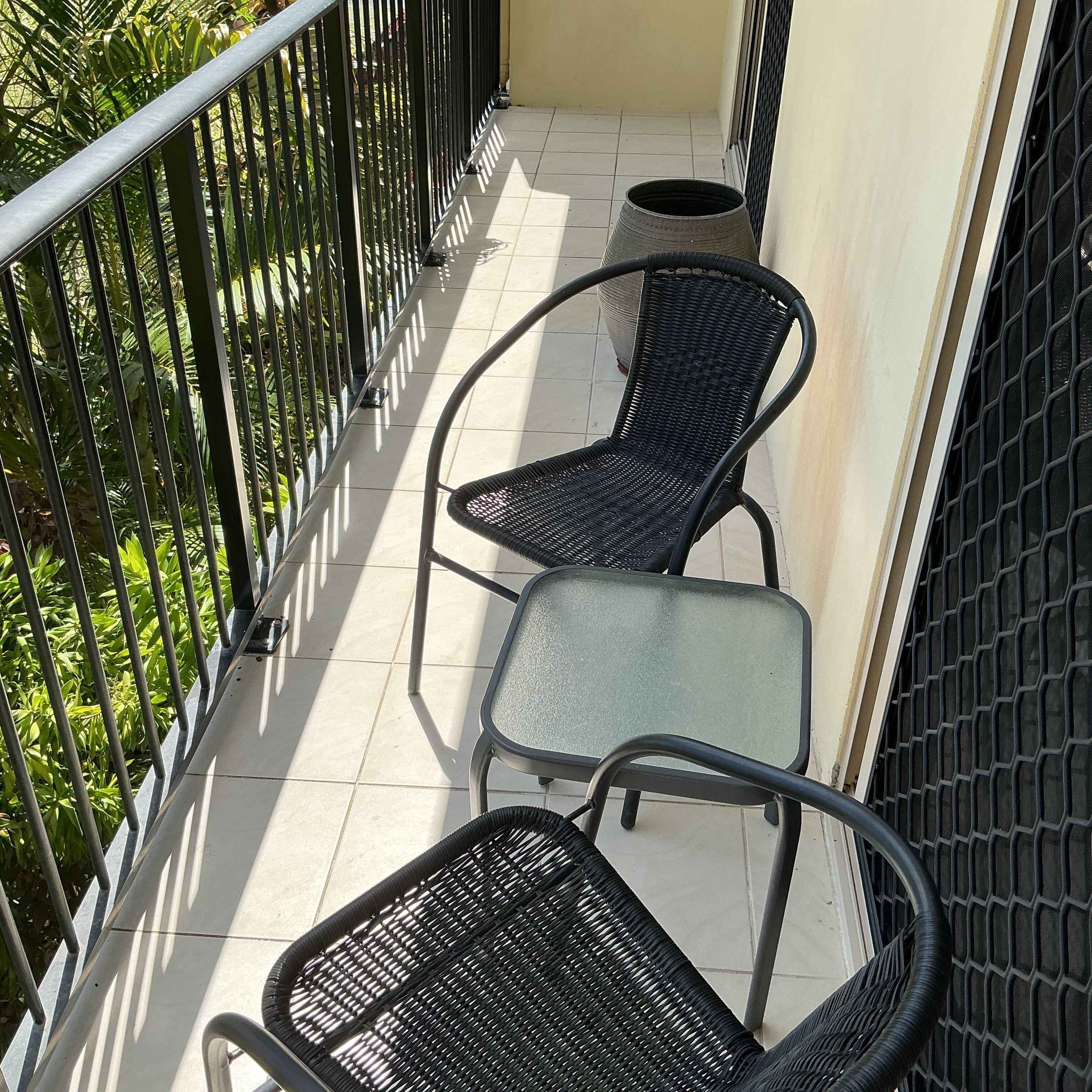 A balcony with two wicker chairs and a small round table.