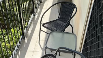 A balcony with two wicker chairs and a small round table.