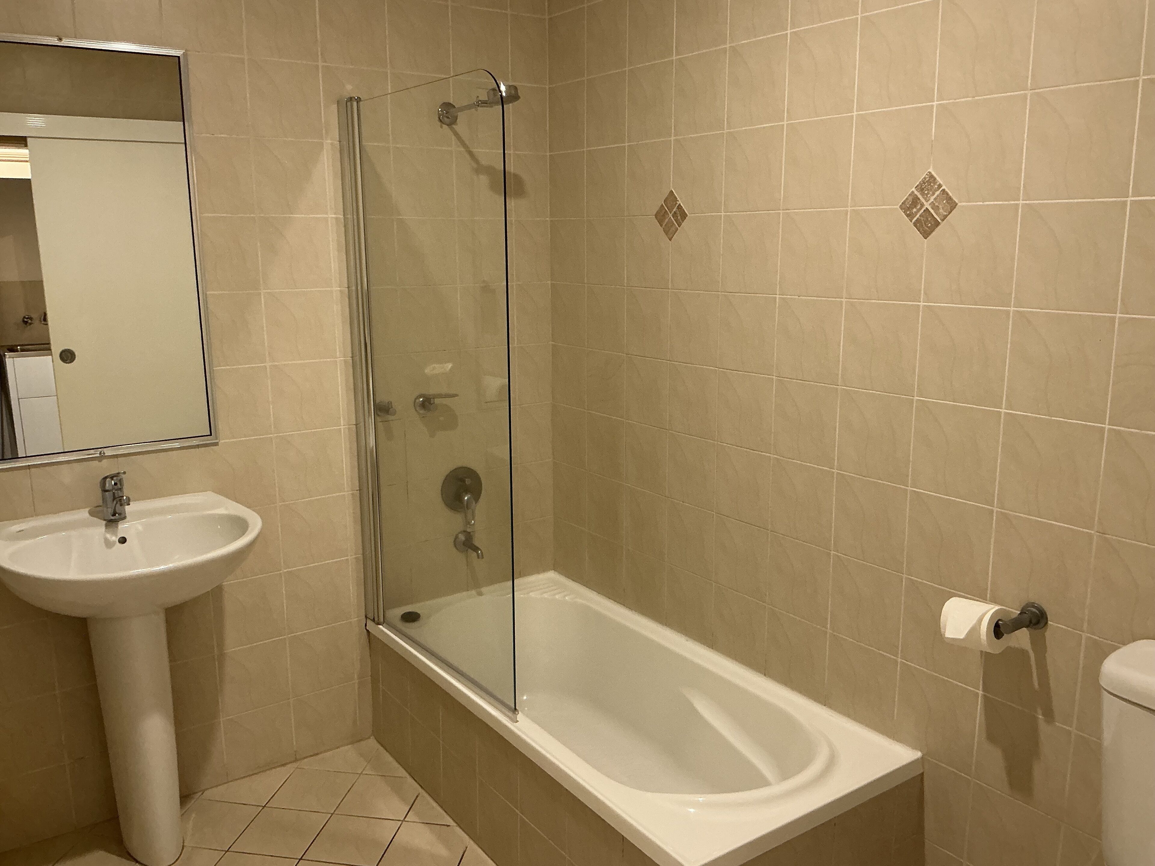 A bathroom with a glass-enclosed shower, a pedestal sink, and a toilet.