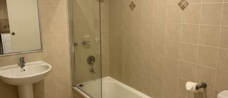 Une salle de bain avec une douche à parois de verre, un lavabo sur colonne et des toilettes.