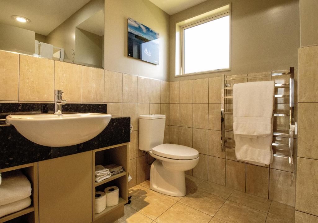 A bathroom with a sink, toilet, and towel rack.