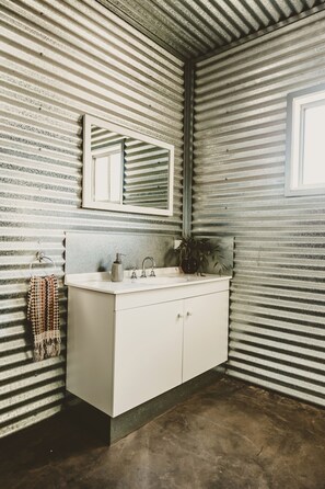 A bathroom with a white vanity, a mirror, a sink, and a towel rack. - Corynnia Station (Carrathool)