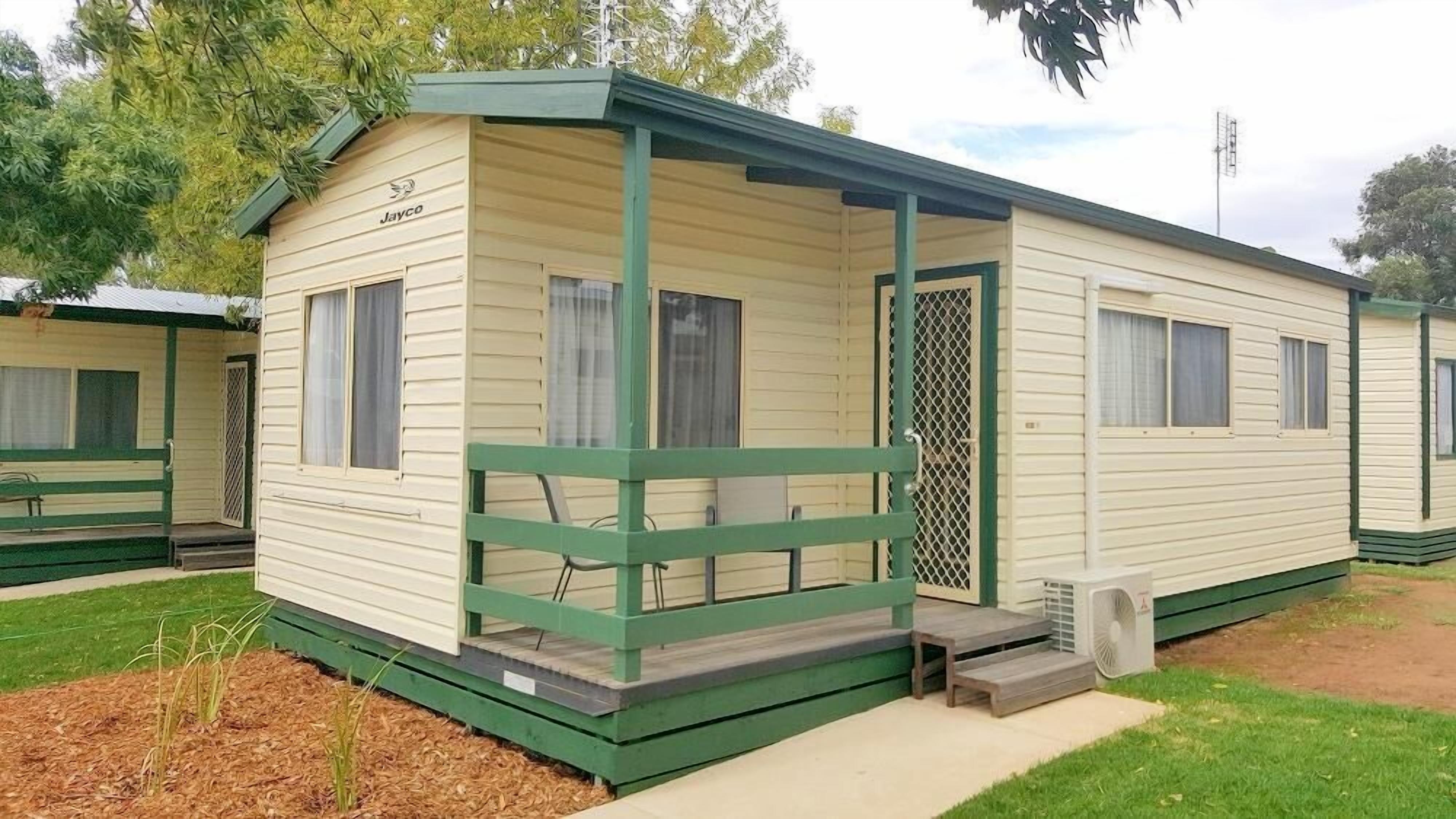 Une maison mobile dotée d’une véranda, d’un petit escalier et d’un ventilateur.