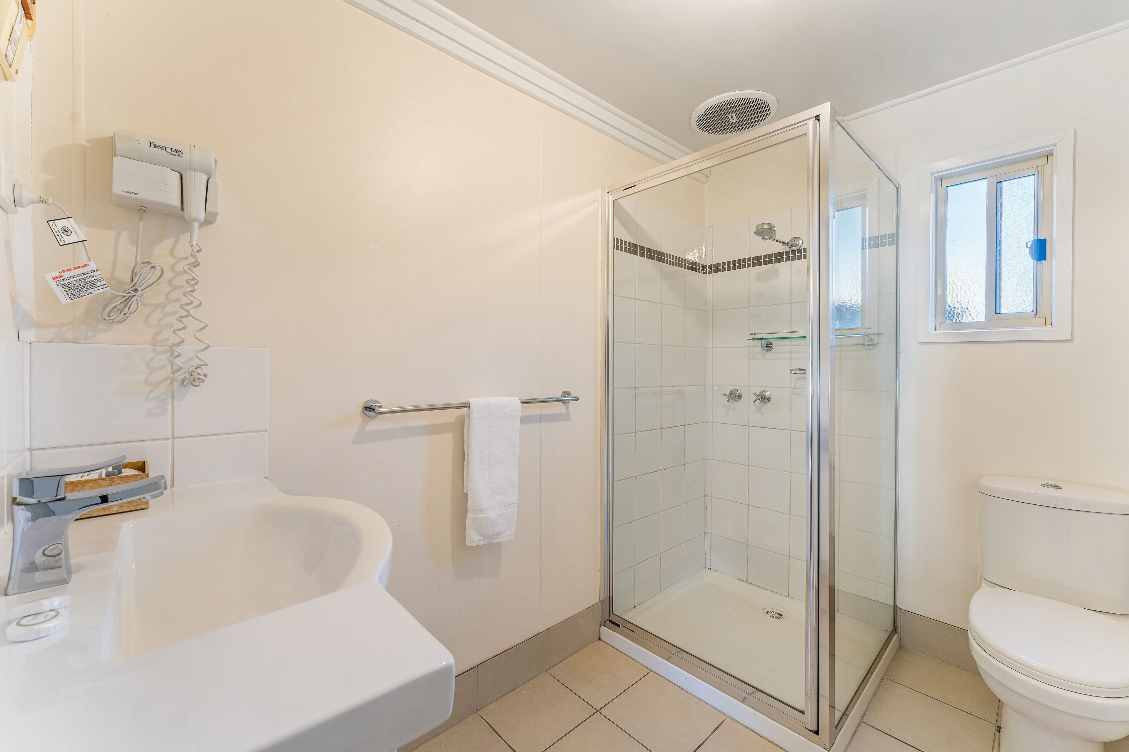 A bathroom with a glass-enclosed shower, a white bathtub, and a toilet.