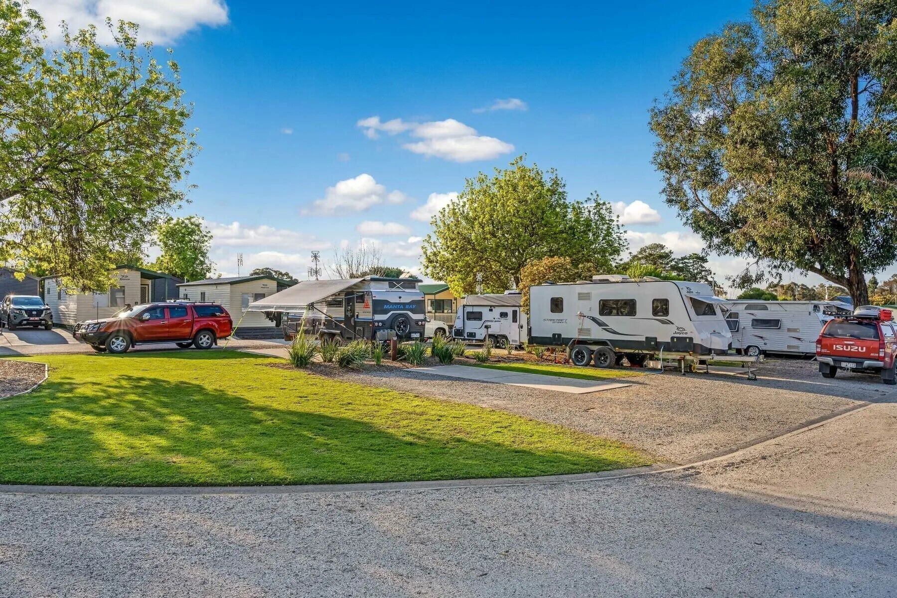 A caravan park with RVs, a red SUV, and mobile homes.