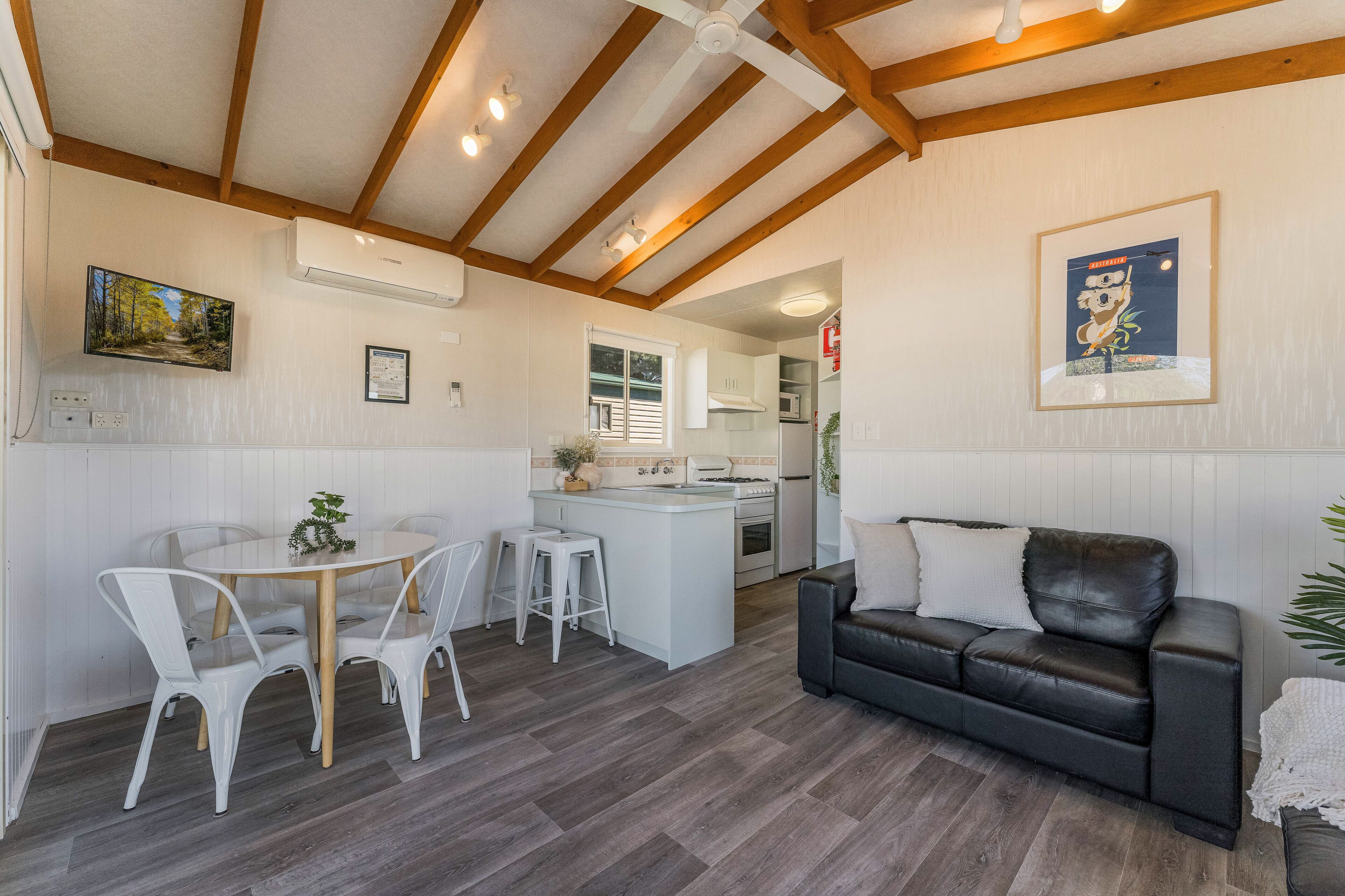 A modern kitchen with white cabinets, a central island, and a dining area with white chairs.