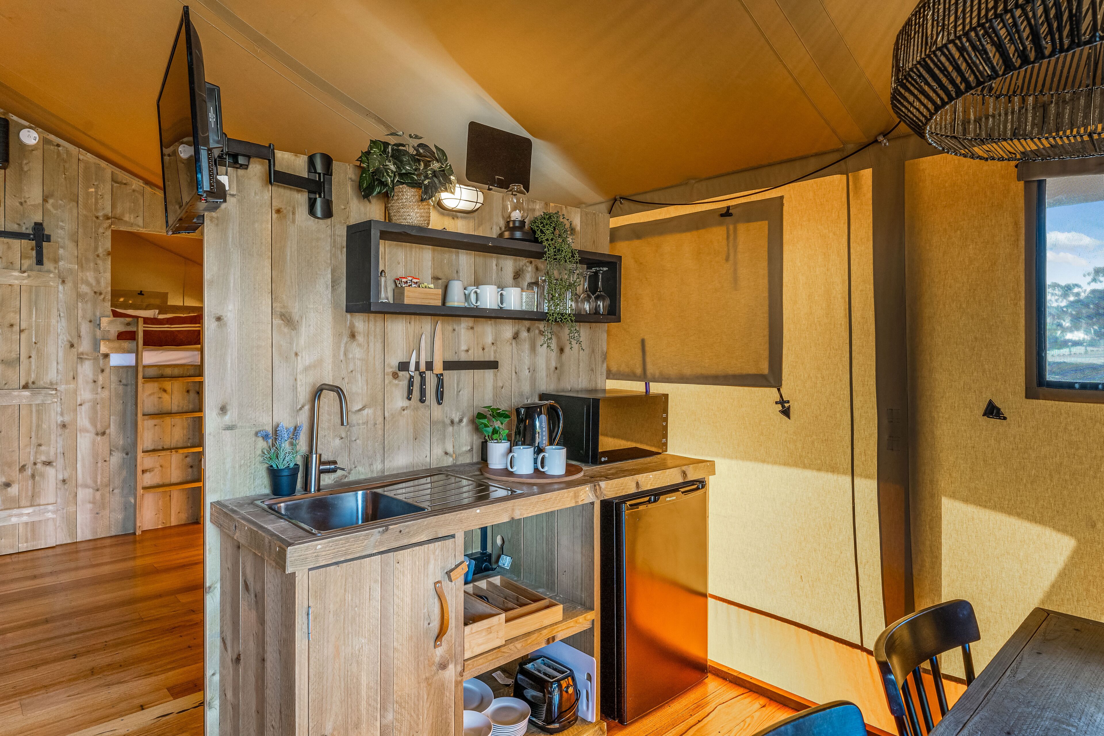 A compact kitchen with wooden cabinetry, a built-in sink, and a compact refrigerator.