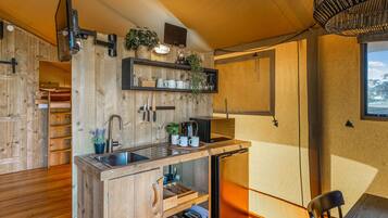 Een kleine keuken met houten kastjes, een inbouwgootsteen en een compacte koelkast.