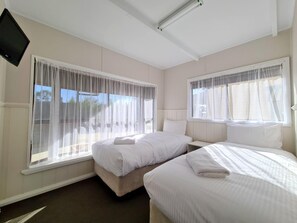 A hotel room with two beds, a flat-screen TV, and large windows with sheer curtains. - BIG4 Tasman Holiday Parks - Bendigo (White Hills)