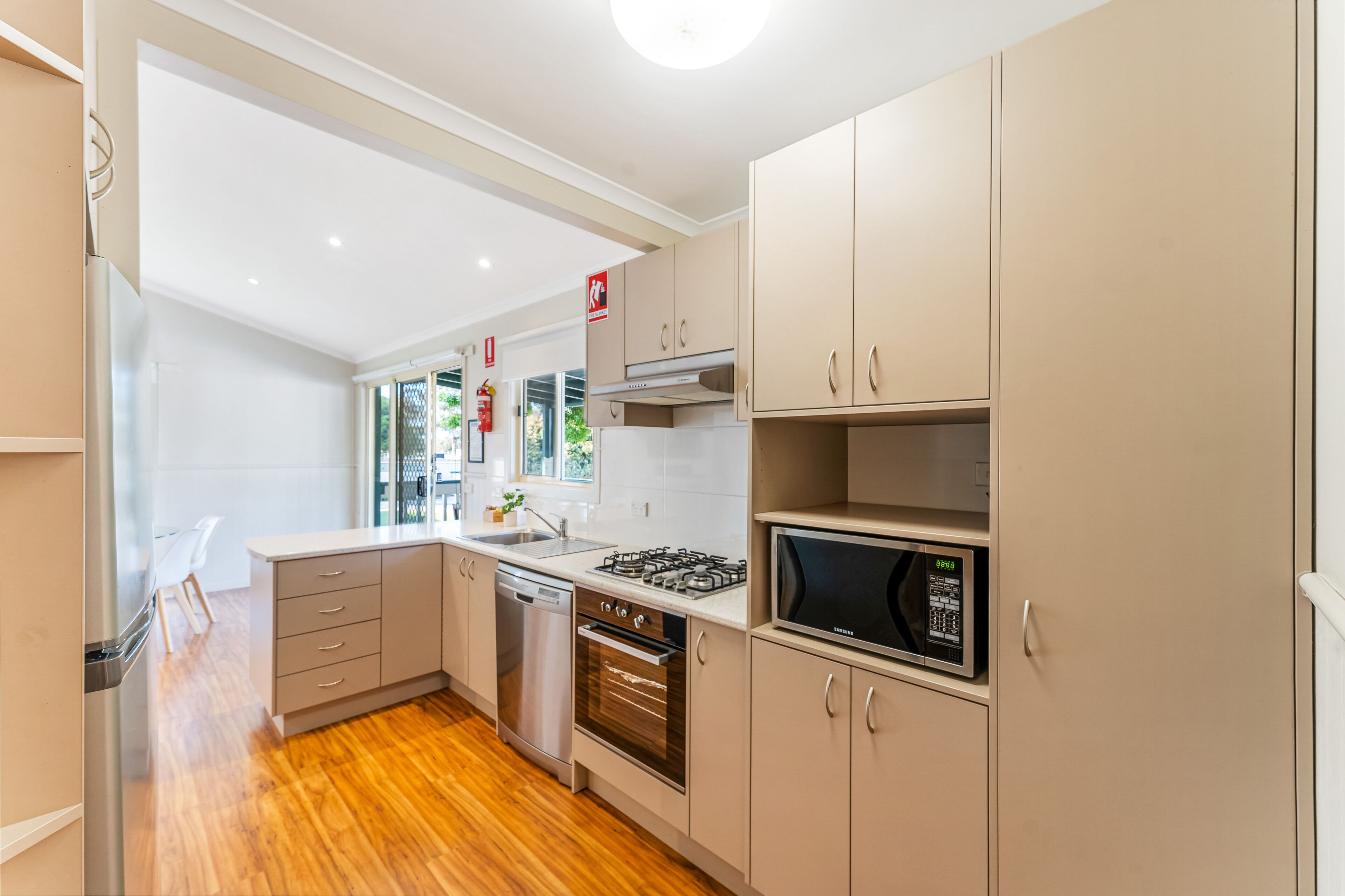 Una cocina moderna con electrodomésticos de acero inoxidable, piso de madera y armarios de colores claros.