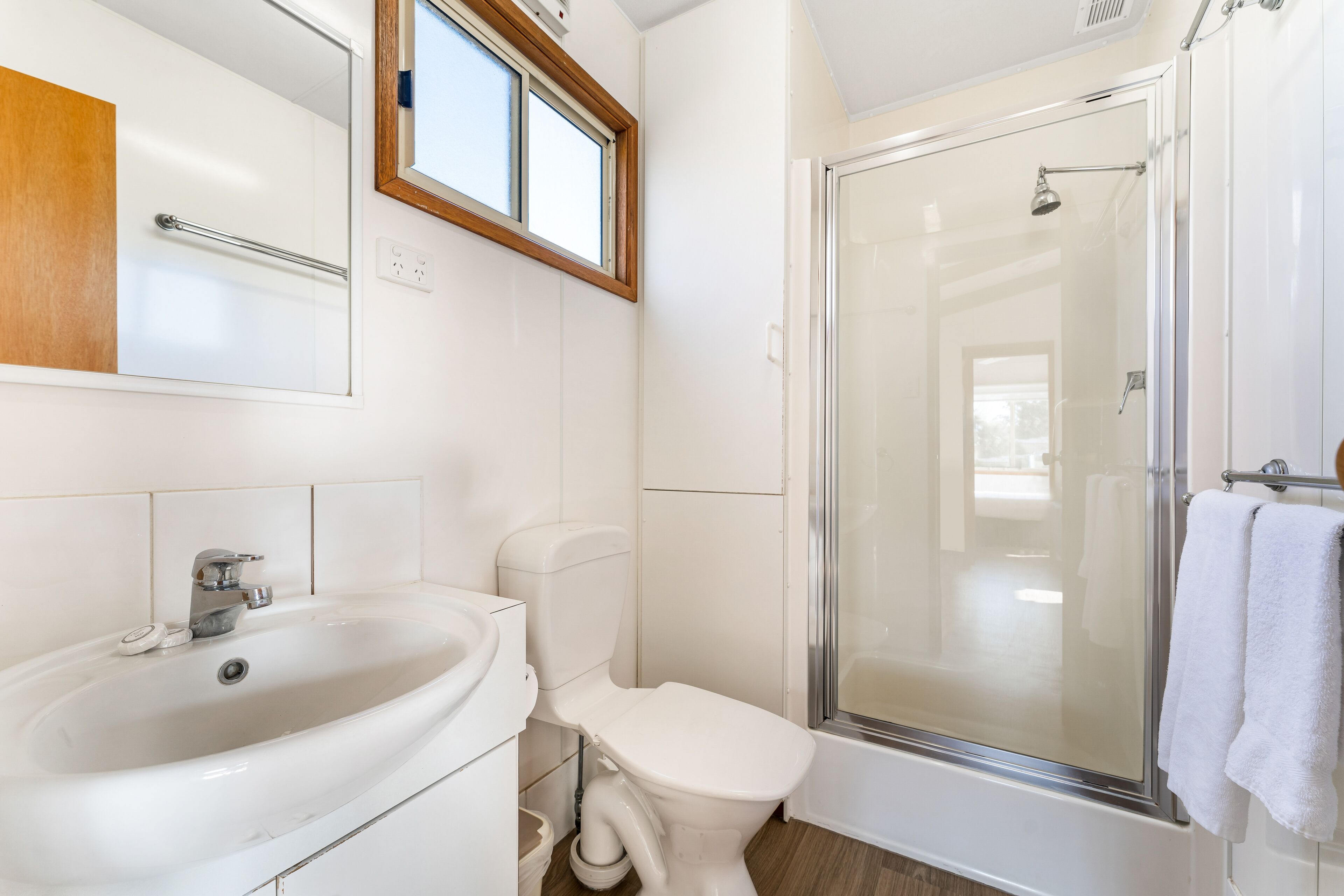Une salle de bain équipée d’un lavabo, de toilettes et d’une douche à parois de verre.