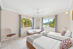 A hotel room with two beds, a chair, and large windows.