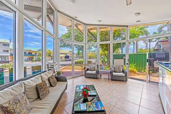 A spacious room with large windows, a sofa with patterned cushions, a coffee table with a decorative item, and a view of the outside.