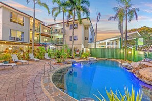 A pool area with lounge chairs, a pool, and a building with balconies. - Koala Court Holiday Apartments (Cairns North)