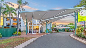 A hotel entrance with a covered walkway, a signboard, and a parking area. - Koala Court Holiday Apartments (Cairns North)