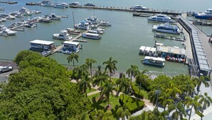 A marina with various boats docked, surrounded by lush greenery and mountains in the background. - Koala Court Holiday Apartments (Cairns North)